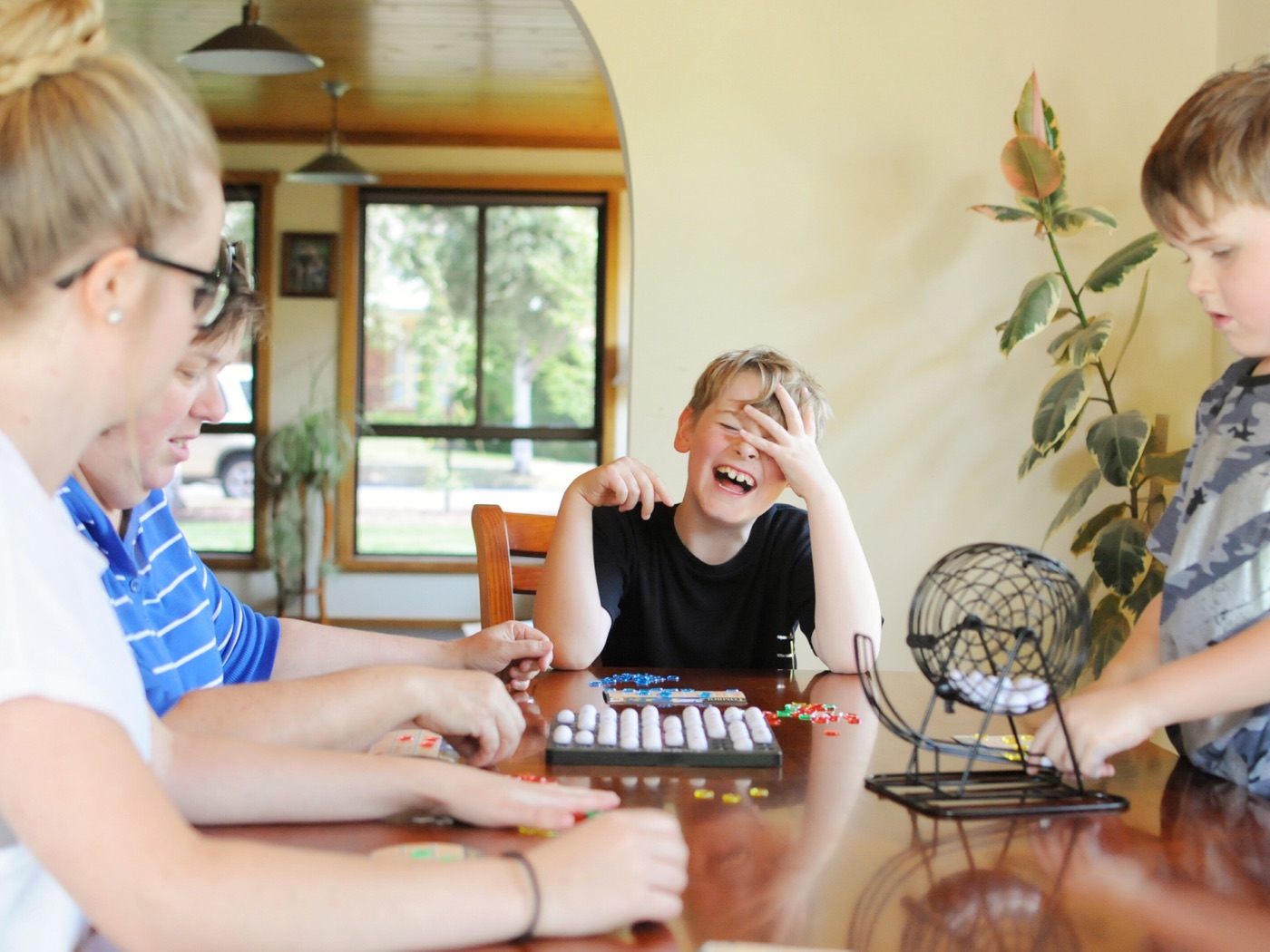 Eine Familie sitzt um einen Tisch, ein Junge lacht beim Spielen