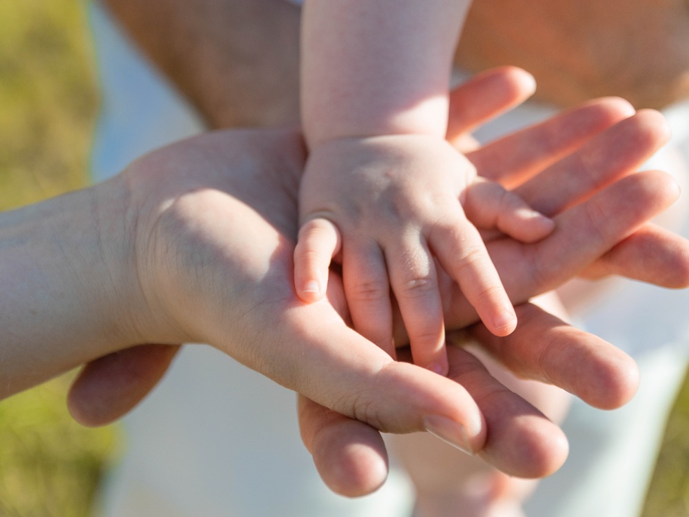 Eine kleine Kinderhand liegt in der Hand eines Erwachsenen
